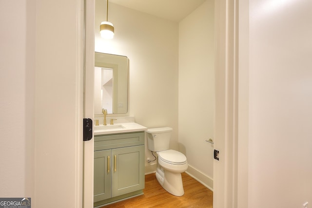 bathroom with toilet, vanity, and hardwood / wood-style flooring