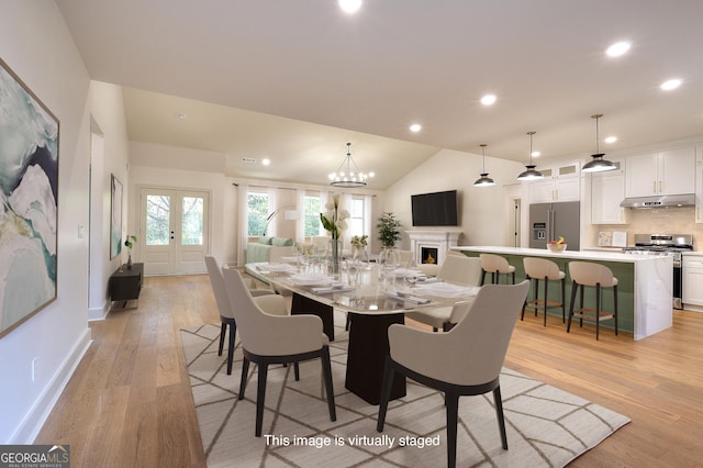 dining area with light hardwood / wood-style floors, lofted ceiling, and an inviting chandelier