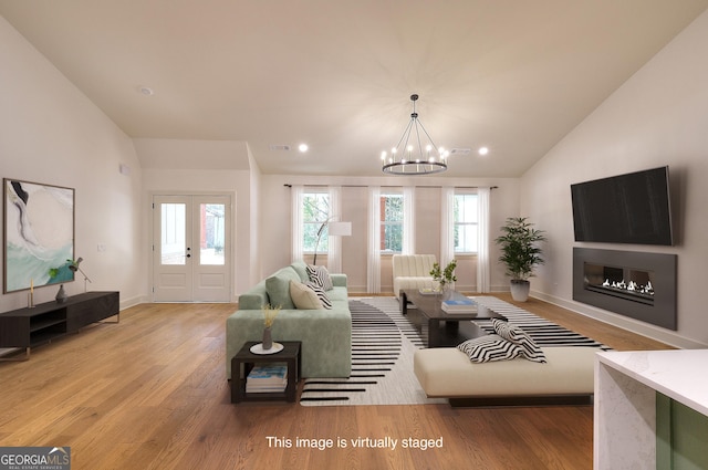 living room with french doors, light wood-type flooring, vaulted ceiling, and a notable chandelier