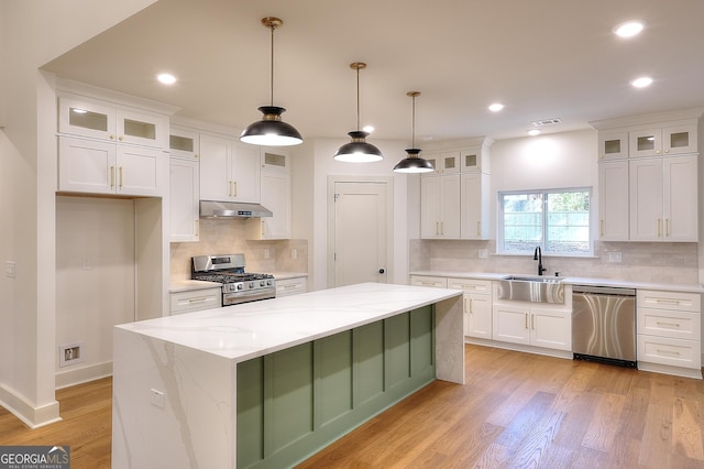 kitchen featuring light stone counters, a center island, white cabinets, and stainless steel appliances