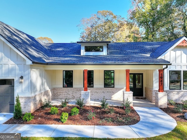 view of front facade featuring a garage, covered porch, and french doors