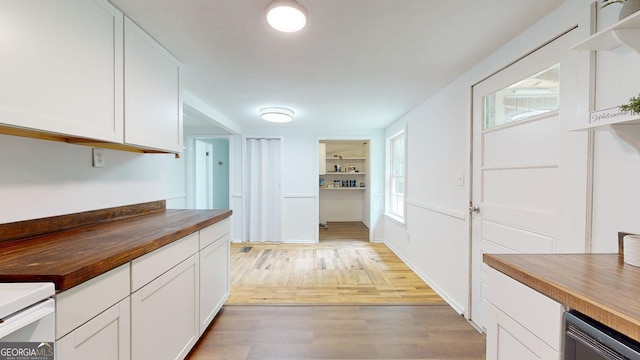 kitchen with stove, white cabinets, wooden counters, and light wood-type flooring