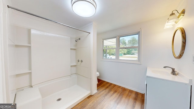 bathroom featuring a shower, wood-type flooring, vanity, and toilet