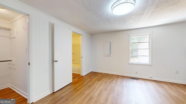 unfurnished bedroom featuring ornamental molding, a walk in closet, light hardwood / wood-style flooring, and a closet