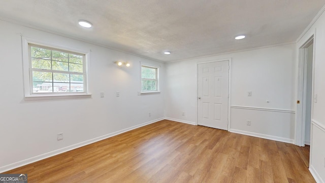 unfurnished room with crown molding, light hardwood / wood-style flooring, and a textured ceiling