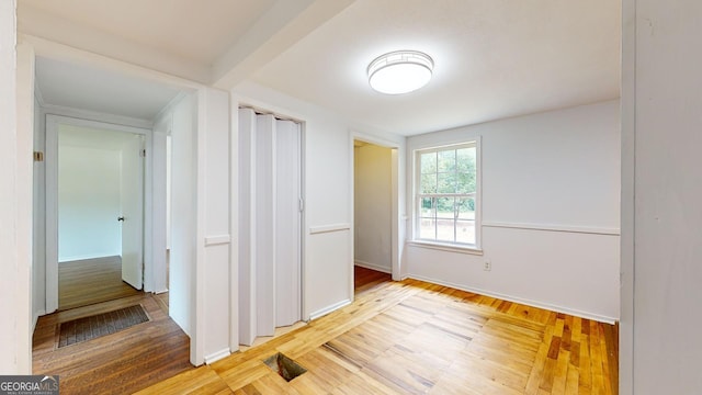 interior space with beam ceiling and light hardwood / wood-style flooring