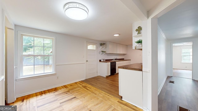 kitchen with sink, white cabinetry, black dishwasher, and light hardwood / wood-style flooring