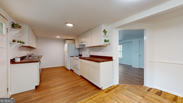 kitchen with wood counters, white appliances, sink, white cabinets, and light hardwood / wood-style floors