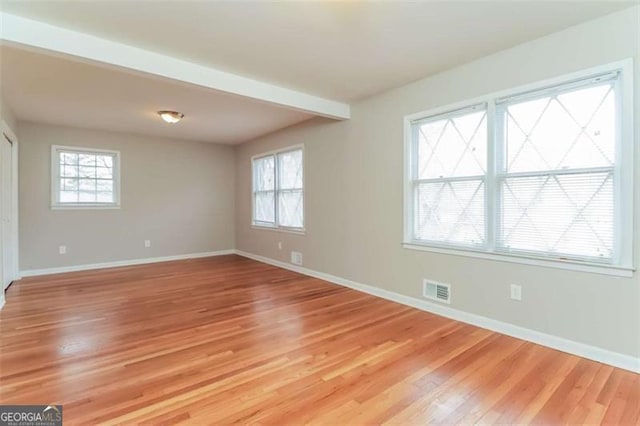 unfurnished room with light hardwood / wood-style flooring and beam ceiling