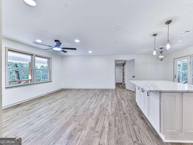 unfurnished living room featuring a wealth of natural light, light hardwood / wood-style flooring, and ceiling fan