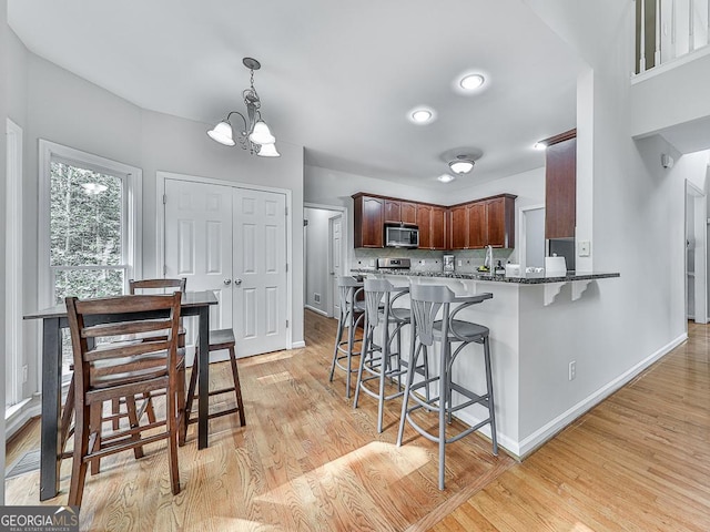 kitchen with pendant lighting, light hardwood / wood-style floors, a kitchen bar, and an inviting chandelier