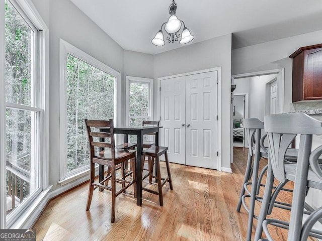 dining space with a wealth of natural light, light hardwood / wood-style floors, and a notable chandelier