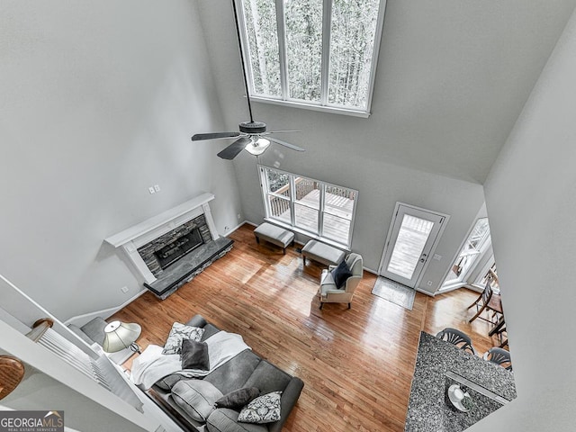 living room featuring a fireplace, a towering ceiling, ceiling fan, and a healthy amount of sunlight