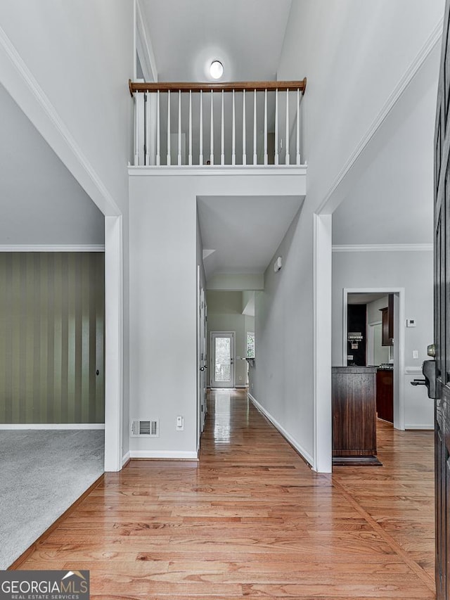 foyer featuring a towering ceiling, hardwood / wood-style flooring, and crown molding