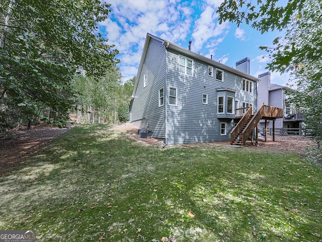 rear view of property featuring a deck and a lawn