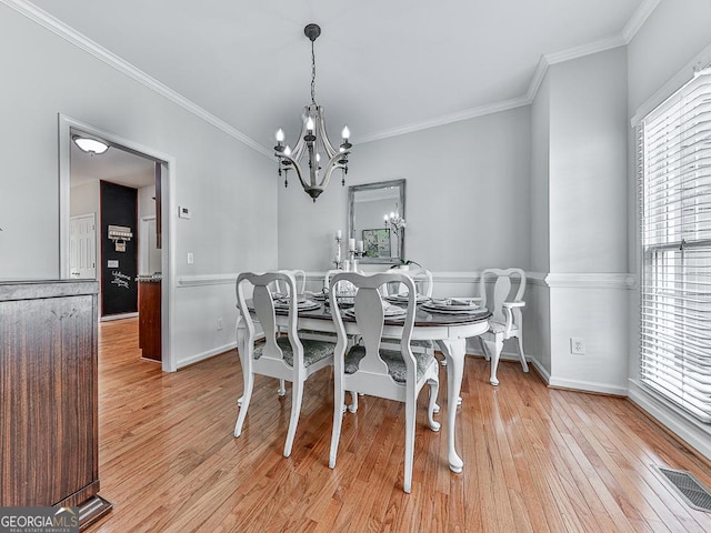 dining space featuring a chandelier, light hardwood / wood-style flooring, and crown molding