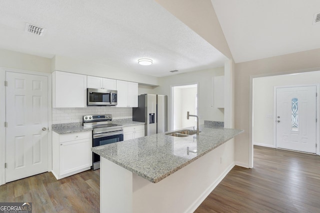 kitchen with white cabinetry, sink, stainless steel appliances, light stone counters, and kitchen peninsula