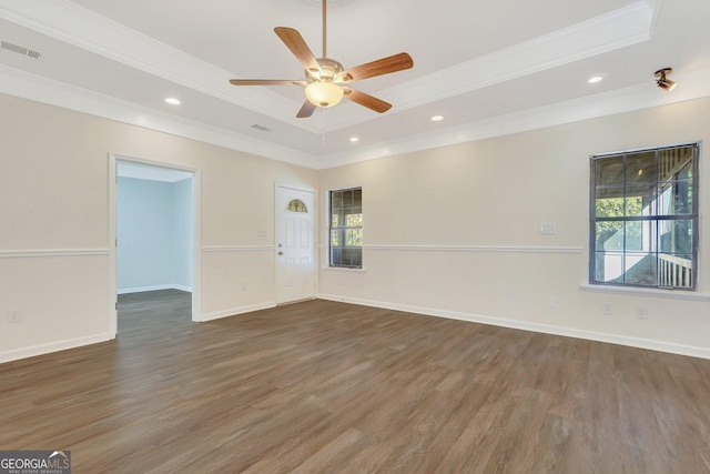 empty room featuring a tray ceiling, ceiling fan, dark hardwood / wood-style flooring, and a healthy amount of sunlight