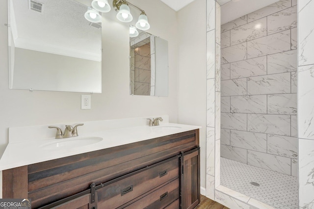 bathroom featuring a tile shower and vanity