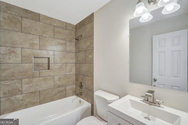 full bathroom with vanity, toilet, a textured ceiling, and tiled shower / bath