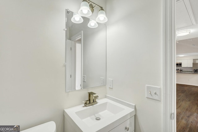 bathroom with hardwood / wood-style floors, vanity, and toilet