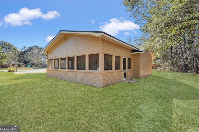 view of home's exterior featuring a lawn and a sunroom