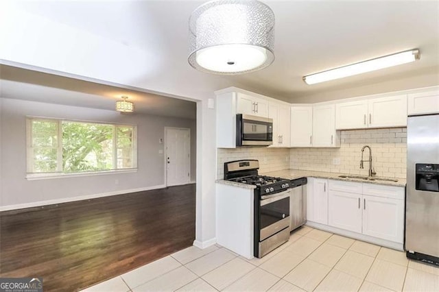 kitchen with light stone countertops, sink, stainless steel appliances, and white cabinetry