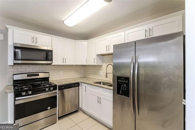 kitchen featuring light stone countertops, white cabinetry, light tile patterned floors, and stainless steel appliances