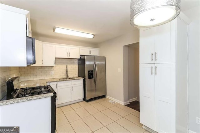 kitchen featuring appliances with stainless steel finishes, decorative backsplash, white cabinets, light stone counters, and sink