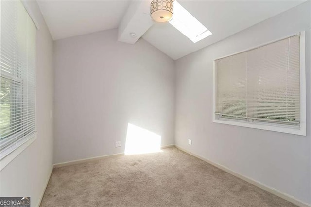 spare room with lofted ceiling with skylight and light carpet