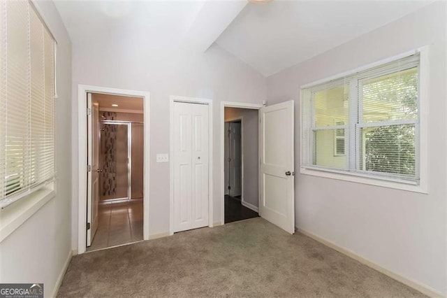 unfurnished bedroom with carpet, ensuite bathroom, and vaulted ceiling