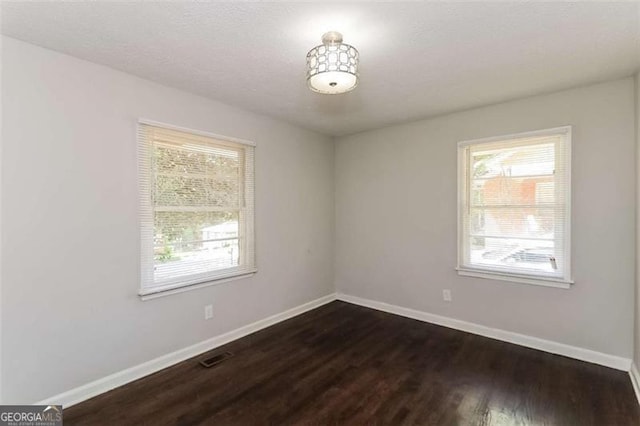 unfurnished room with dark wood-type flooring and plenty of natural light