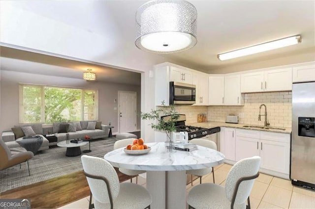 kitchen with white cabinetry, stainless steel appliances, decorative backsplash, light stone countertops, and sink