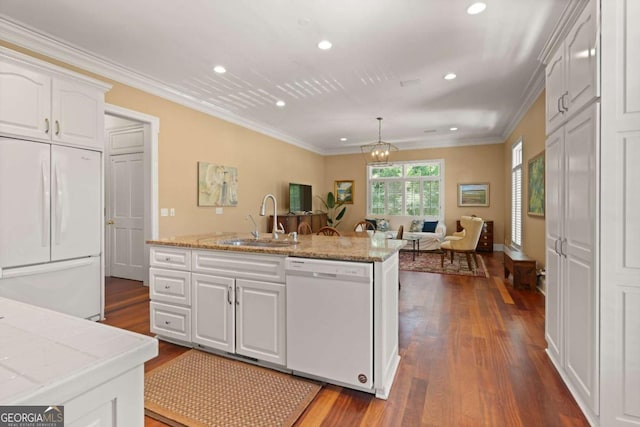 kitchen featuring white cabinetry, sink, decorative light fixtures, white appliances, and a kitchen island with sink