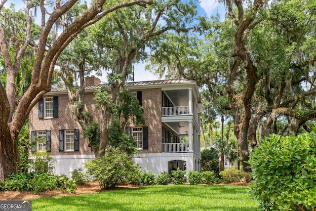 rear view of house featuring a yard and a balcony