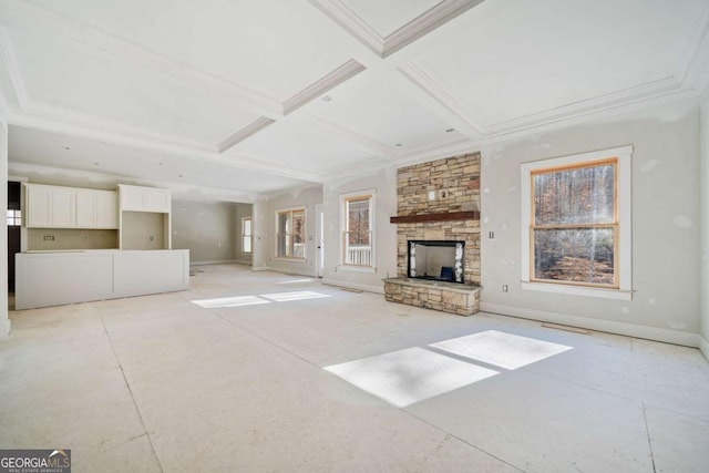 unfurnished living room with beamed ceiling, a stone fireplace, coffered ceiling, and crown molding