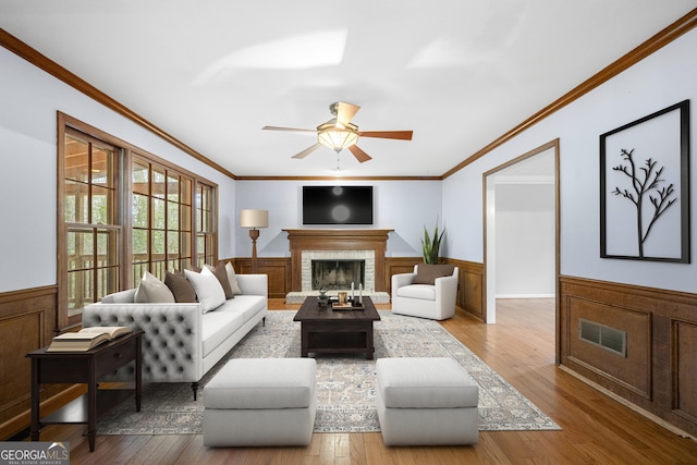 living room featuring a fireplace, crown molding, and light hardwood / wood-style flooring