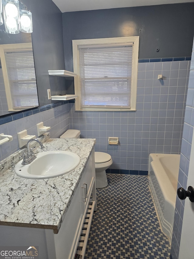 bathroom with vanity, a bath, tile walls, and toilet