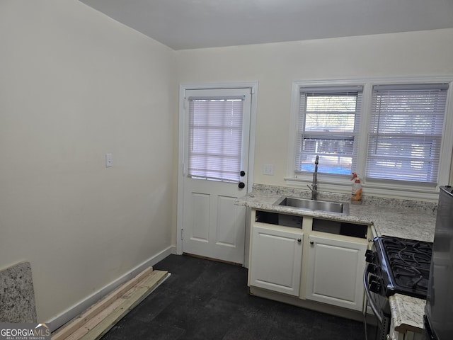 kitchen featuring white cabinets, black range with gas cooktop, light stone countertops, and sink