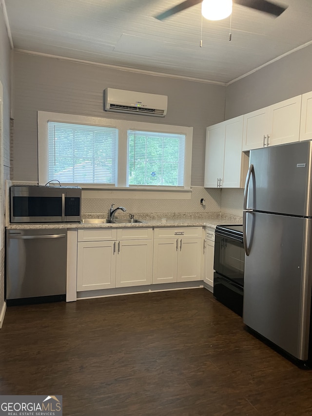 kitchen featuring an AC wall unit, white cabinetry, plenty of natural light, and appliances with stainless steel finishes