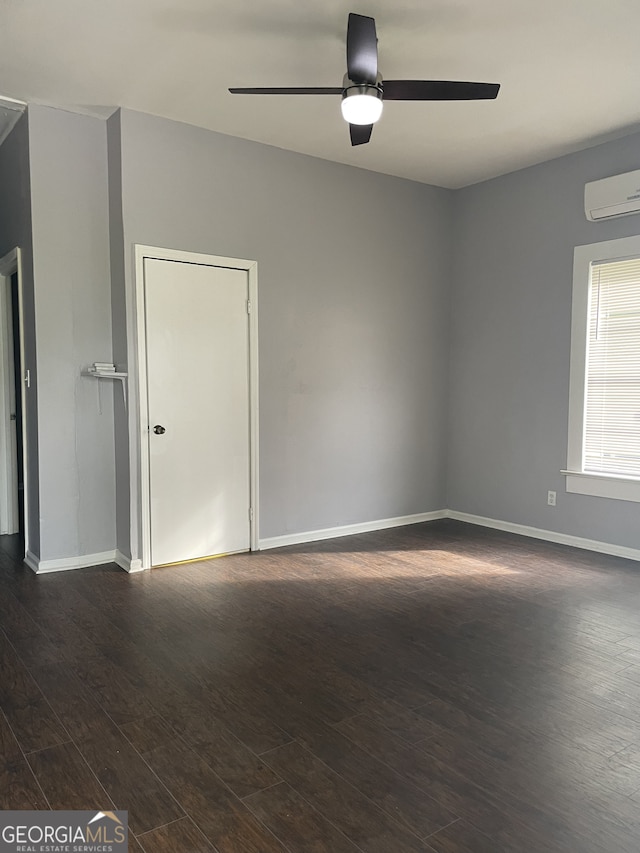 empty room featuring ceiling fan, dark hardwood / wood-style flooring, and a wall unit AC