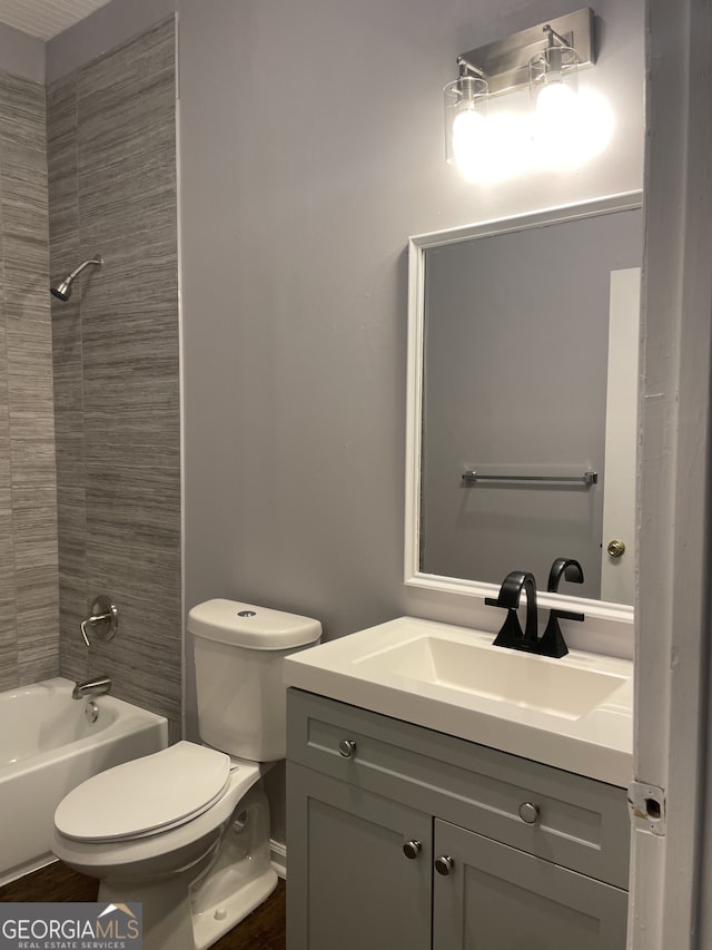 full bathroom featuring tiled shower / bath combo, toilet, and vanity