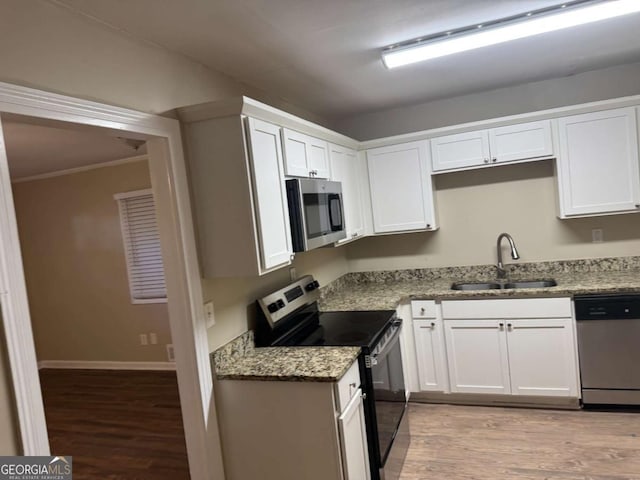 kitchen with white cabinets, sink, light hardwood / wood-style floors, light stone counters, and stainless steel appliances