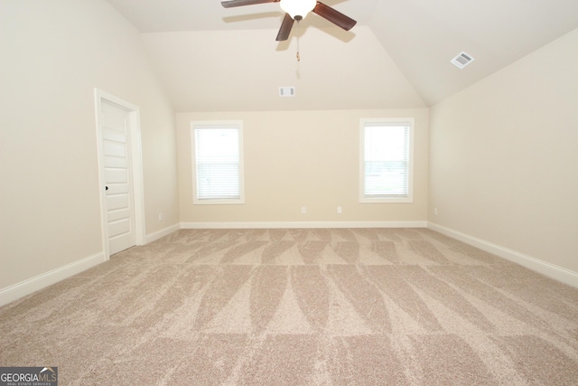 carpeted spare room featuring ceiling fan, a healthy amount of sunlight, and lofted ceiling