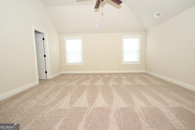 spare room with light colored carpet, a wealth of natural light, and vaulted ceiling