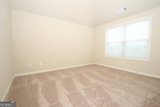 spare room featuring carpet and vaulted ceiling