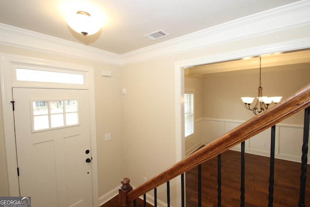 entrance foyer with dark hardwood / wood-style flooring, crown molding, and an inviting chandelier