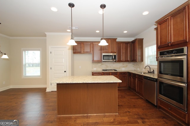 kitchen featuring decorative light fixtures, a center island, light stone countertops, and appliances with stainless steel finishes