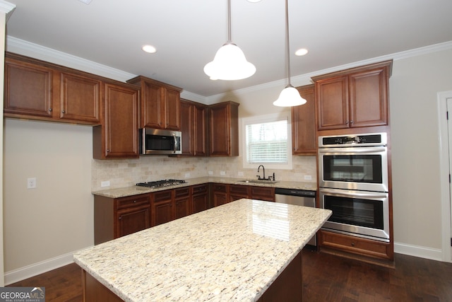 kitchen featuring light stone countertops, hanging light fixtures, stainless steel appliances, and sink