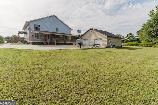 back of house with a porch, a garage, a yard, and an outbuilding